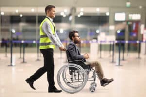 man being pushed in a wheelchair in an airport after knee replacement