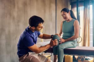 physical therapist treating a woman with osteoarthritis in her knee
